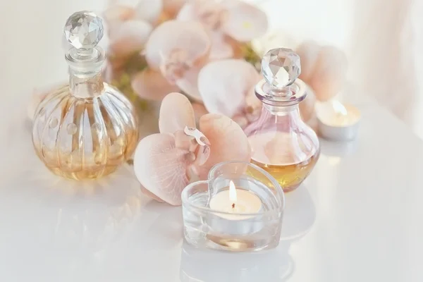 Zapachowych i aromatycznych olejów butelek otoczony kwiatami i cand — Zdjęcie stockowe
