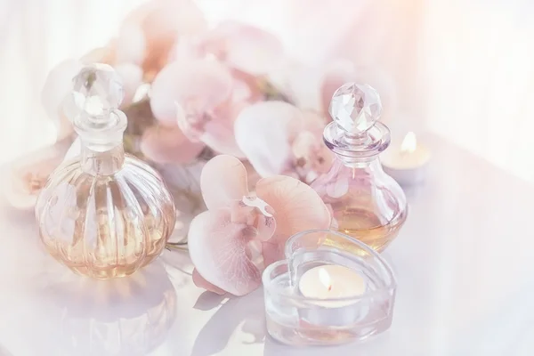 Perfume and aromatic oils bottles surrounded by flowers and cand — Stock Photo, Image