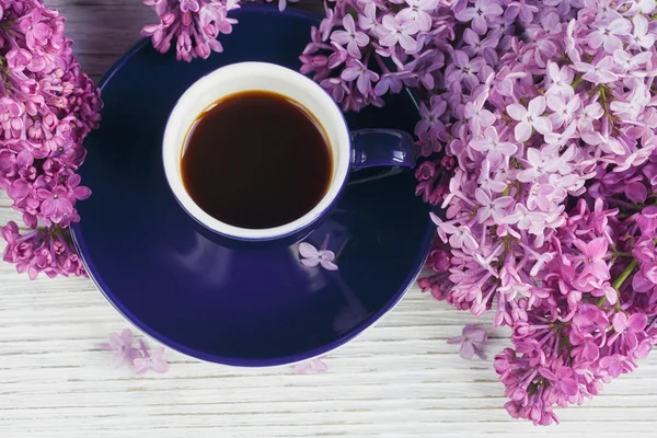 Tasse schwarzen Kaffee, fliederfarbene Blumen und süße pastellfarbene Macar — Stockfoto