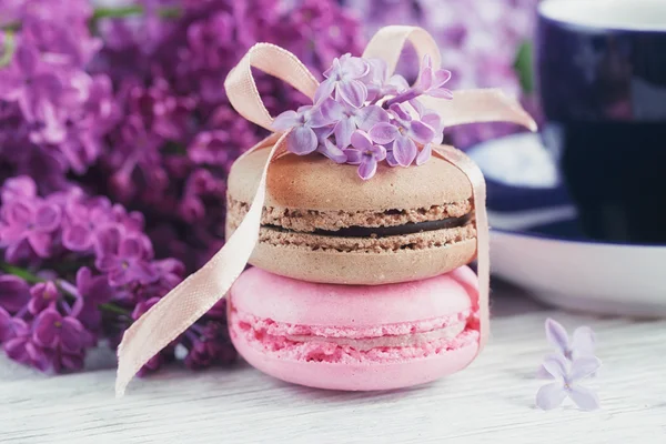 Xícara de café preto, flores lilás e doce macar francês pastel — Fotografia de Stock