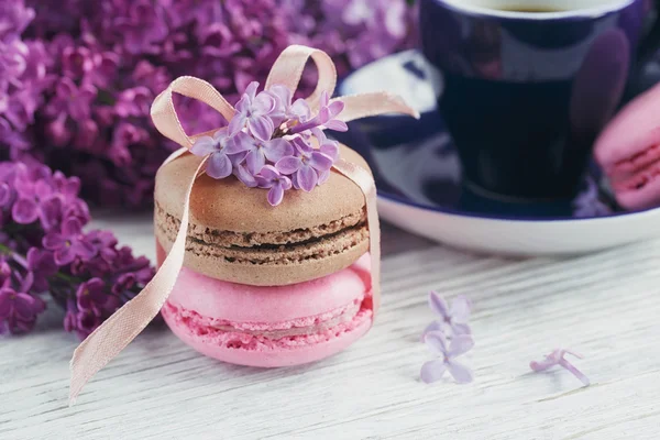 Tasse schwarzen Kaffee, fliederfarbene Blumen und süße pastellfarbene Macar — Stockfoto