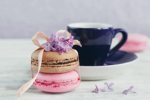 Šálek černé kávy, květy a sladké pastelové francouzské macar — Stock fotografie