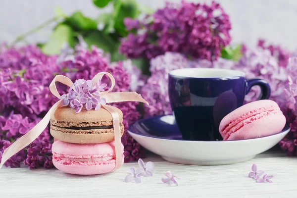 Tasse schwarzen Kaffee, fliederfarbene Blumen und süße pastellfarbene Macar — Stockfoto