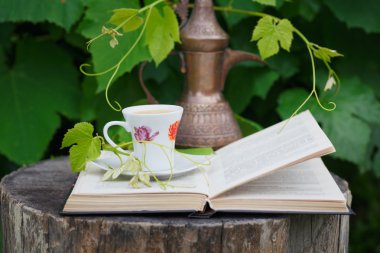 Natürmort antika sürahi, açık kitap ve fincan kahve cov