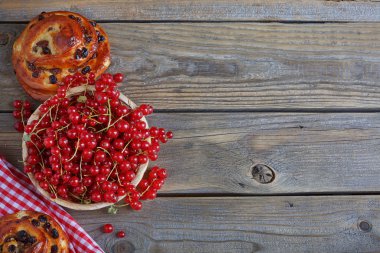 Kahverengi ahşap masa üzerinde kırmızı kuş üzümü ile taze pişmiş çörekler