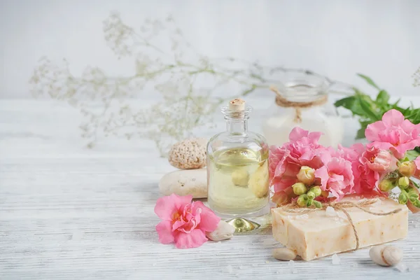 Jabón natural hecho a mano, aceite aromático y flores en madera blanca — Foto de Stock