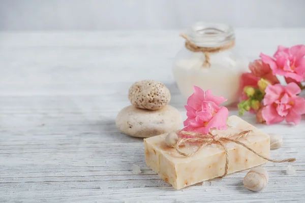 Naturalne mydła ręcznie robione, olejki aromatyczne i kwiaty na biały drewniany — Zdjęcie stockowe