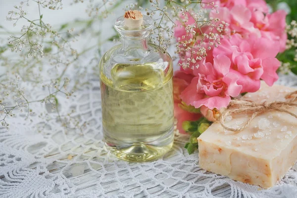 Jabón natural hecho a mano, aceite aromático y flores en madera blanca — Foto de Stock