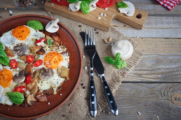 Ovos fritos com cogumelos, tomates e manjericão em t de madeira rústica — Fotografia de Stock