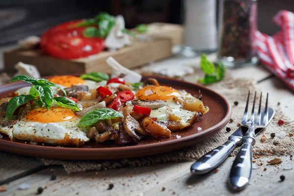 Ovos fritos com cogumelos, tomates e manjericão em t de madeira rústica — Fotografia de Stock