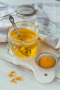 Ev yapımı Ghee ya da tereyağını kavanozda ve zerdeçal beyaz ahşap masada..