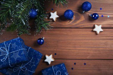 Noel kompozisyonu. Hediyeler, köknar ağacı dalları, ahşap arka planda mavi süslemeler. Noel, kış, yeni yıl tatili konsepti. Düz konum, üst görünüm, kopyalama alanı