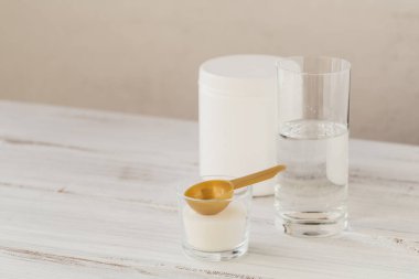 Kasede kolajen tozu, bir bardak su ve tahta zemin üzerinde kaşık ölçüsü. Fazladan protein alımı. Doğal güzellik ve sağlık takviyesi konsepti.