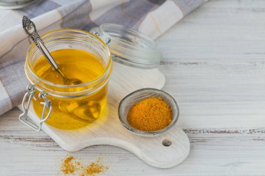 Ev yapımı Ghee ya da tereyağını kavanozda ve zerdeçal beyaz ahşap masada..