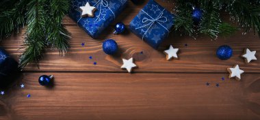Noel kompozisyonu. Hediyeler, köknar ağacı dalları, ahşap arka planda mavi süslemeler. Noel, kış, yeni yıl tatili konsepti. Düz konum, üst görünüm, kopyalama alanı, uzun pankart