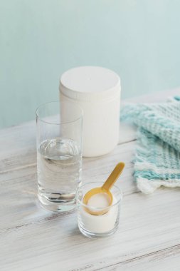 Hidrolize olmuş deniz kaynaklı kolajen peptidler cam kasede ve beyaz ahşap arka planda su. Günlük Ek Konsept.