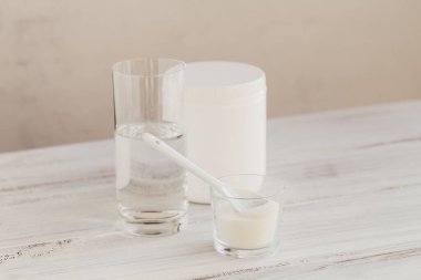 Hidrolize olmuş deniz kaynaklı kolajen peptidler cam kasede ve beyaz ahşap arka planda su. Günlük Ek Konsept.