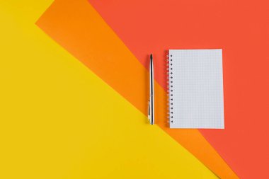 Boş defter ve diğer ofis malzemeleriyle dolu sarı ofis masası. Kopyalama alanı olan üst görünüm, düz yatay.