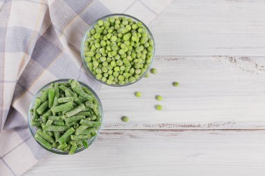 Taze bezelye ve yeşil fasulyeyi kasede kes. Hızlı pişirme için ev yapımı hazırlıklar kavramı. Sağlıklı vejetaryen gıda konsepti. Üst görünüm