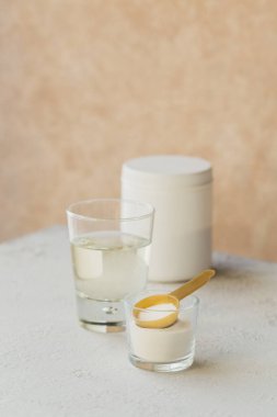 Kolajen içeren cam suda çözünmüş ve kolajen protein tozu açık bej masa üzerinde. Sağlıklı yaşam tarzı kavramı.