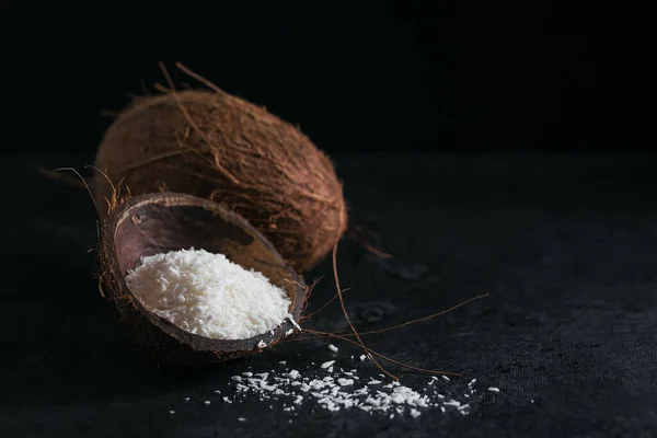 Whole coconut with coconuts flakes on a black background