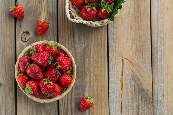 Montón de fresas frescas en una canasta sobre fondo rústico de madera. Alimentación saludable y dieta concepto de alimentos. — Foto de Stock