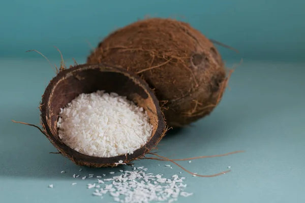 Whole coconut with coconuts flakes on blue background