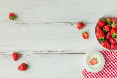 Olgun tatlı böğürtlen ve süt ürünleriyle sade bir kahvaltı. Seramik kasede taze çilek ve beyaz rustik ahşap masada biyo-yoğurt.