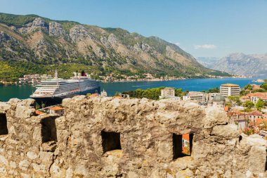 Eski kalelerde, denizlerde, dağlarda, mavi gökyüzünde eski duvarları olan renkli bir manzara. Ortaçağ kalesinden gelen büyük yolcu gemisiyle Kotor Körfezi 'nin üst manzarası. Karadağ 'ın tarihi simgesi
