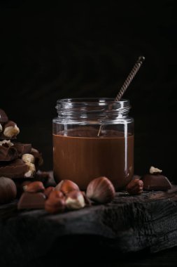 Ev yapımı çikolatalı fındıklı süt. Koyu ahşap arka planda cam kavanoza yayılmış.