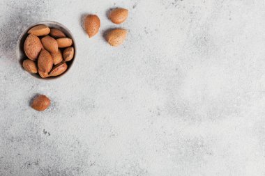 Beyaz arka planda bir kâse dolusu badem fıstığı. Kabuklarında taze fındık. Metin için boş alanı olan üst görünüm