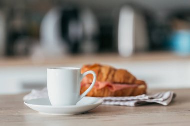breakfast of coffee and croissant sandwich stuffed with salami at the kitchen