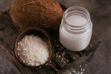 Hindistan cevizi, hindistan cevizi gevreği ve hindistan cevizi yağı kavanozda koyu arka planda. Sağlıklı aşçılık kavramı