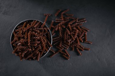 Koyu arkaplanda pişmemiş organik Karabuğday Fusilli makarna. Tam tahıllı glütensiz erişte. Sağlıklı gıda konsepti.