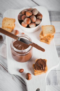 Beyaz ahşap arka planda kahvaltıda fındıklı çikolatalı tost.