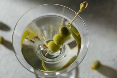 Gri taşlı arka planda zeytinli klasik sek martini kokteyli..