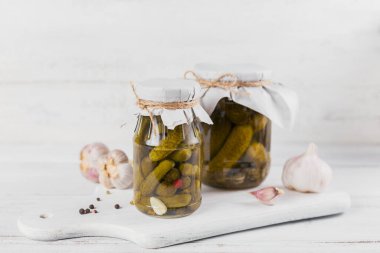 Ev yapımı konserve. Salatalıklı salatalık turşusu, beyaz ahşap masada cam bir kavanozda dereotu ve sarımsak. Kış için sebze salatası..