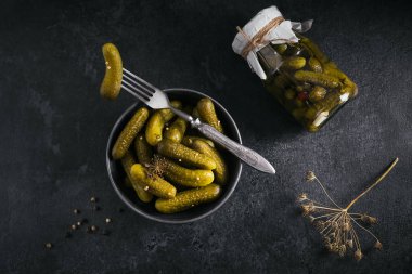 Ev yapımı konserve. Siyah arka planda cam bir kavanozda salatalık salatalığı, dereotlu ve sarımsaklı. Kış için sebze salatası..