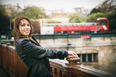 Siyah ceketli esmer kız köprüde duruyor.