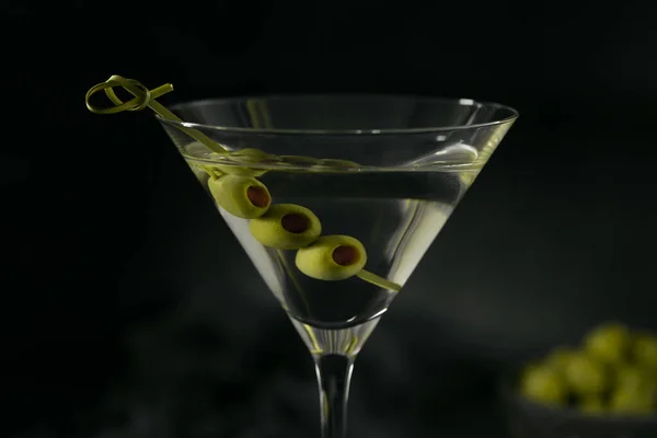 Glas klassischer trockener Martini-Cocktail mit Oliven auf dunklem Steintisch vor schwarzem Hintergrund. — Stockfoto
