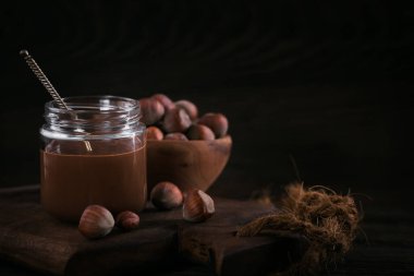 Ev yapımı çikolatalı fındıklı süt. Koyu ahşap arka planda cam kavanoza yayılmış.