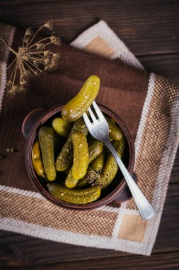 Çömlek, çatalda salatalık turşusu, ahşap arka planda marine edilmiş sebze kasesi. Temiz yemek, vejetaryen yemek konsepti