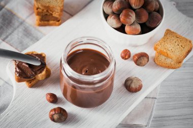 Beyaz ahşap arka planda kahvaltıda fındıklı çikolatalı tost.