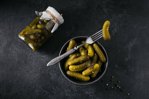 Preserving pickled cucumbers, seasonings and garlic on a dark table. Healthy fermented food. Home canned vegetables.