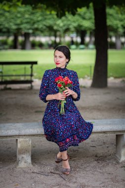 Parkta oturan mavi elbiseli çekici kadın.