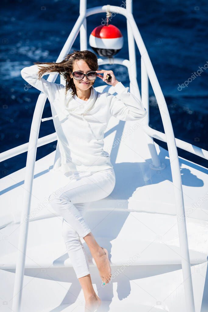 Woman relaxing on the nose of the yacht at a sunny summer day at sea