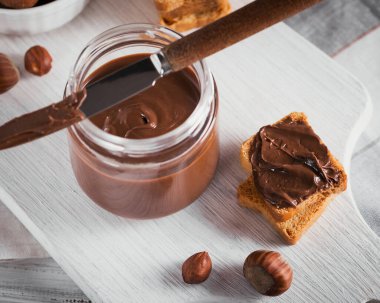 Beyaz ahşap arka planda kahvaltıda fındıklı çikolatalı tost.