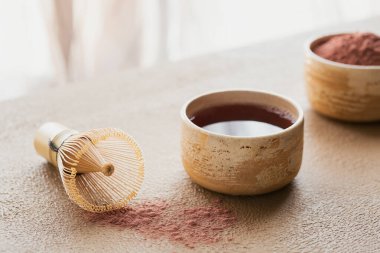 Bej arka planda Japon aletleriyle organik renk tozu çayı Matcha. Vejetaryen sağlıklı içeceği ve içeceği hesaba katın.