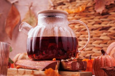 Buharlı bir çaydanlıkta, balkabakları, kurumuş yapraklar ve sıcacık sonbahar dekorlarıyla çevrili sıcak bitki çayının detaylı görüntüsü..