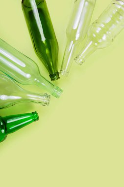 Yumuşak pastel yeşil arka plana yerleştirilmiş yeşil tonlarda cam şişelerin dikey düzenlenmesi